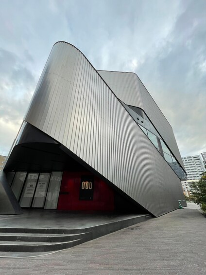 A modern architectural building with a curved facade and a red entrance. 2