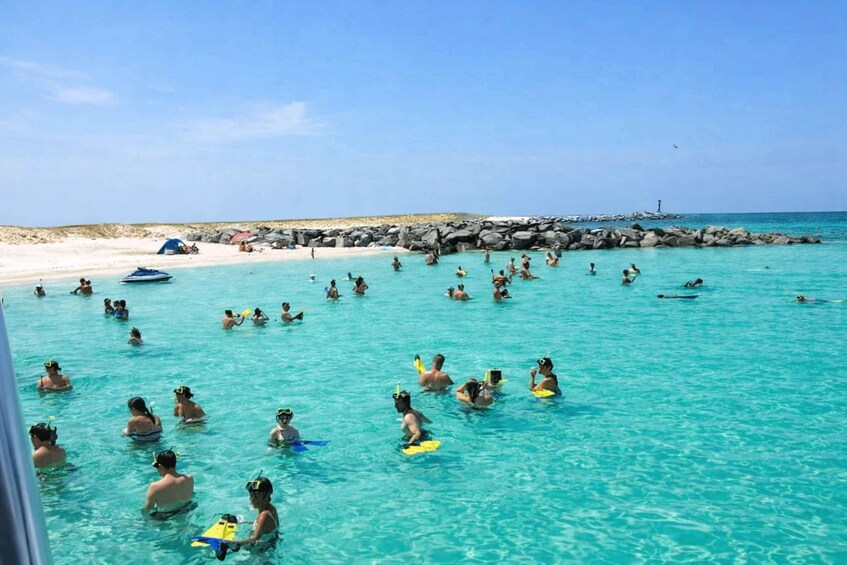A beach with people swimming and snorkeling in clear turquoise water. 1