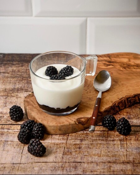 A glass of yogurt with blackberries on a wooden board. 4
