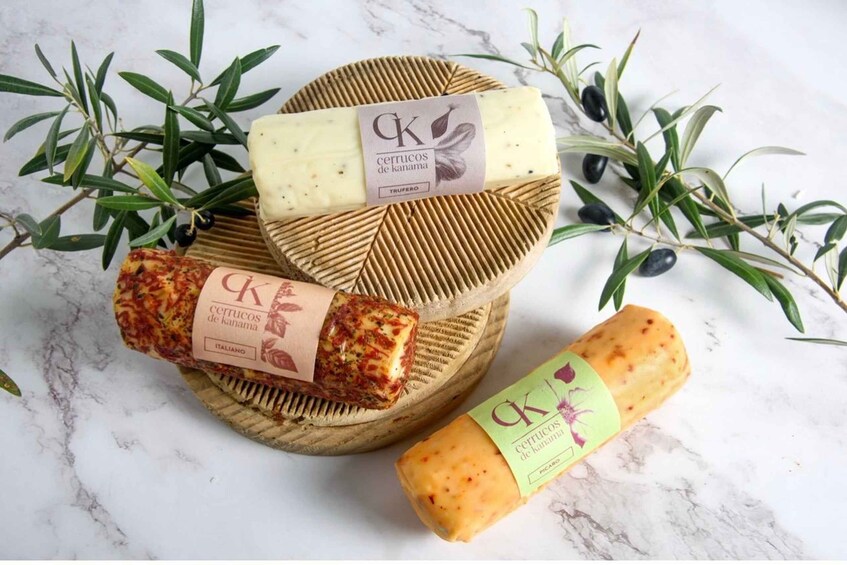 Three types of cheese on a wooden board with olive branches. 5