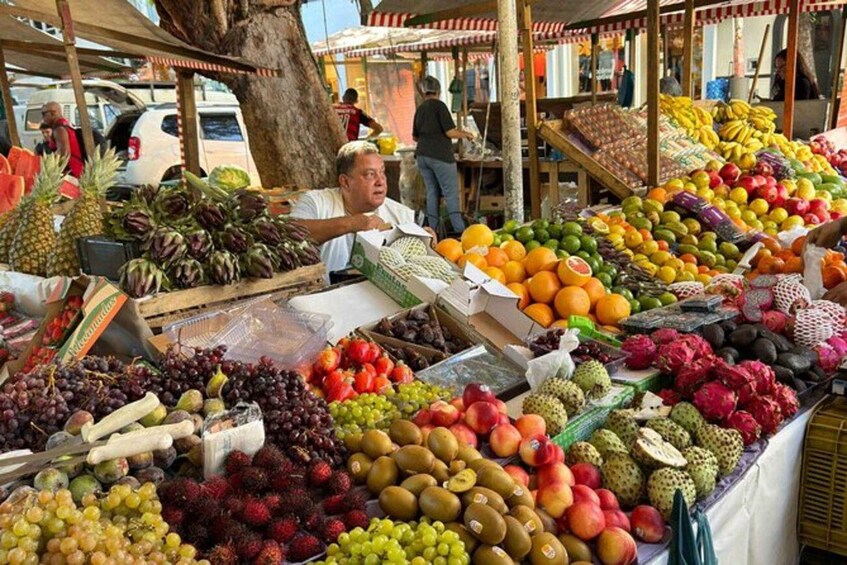 A fruit market with various fruits like pineapples, grapes, and dragon fruits. 1