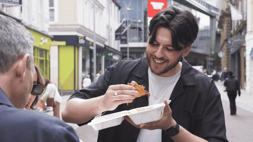 A person eating a slice of pizza outdoors in an urban setting. 2