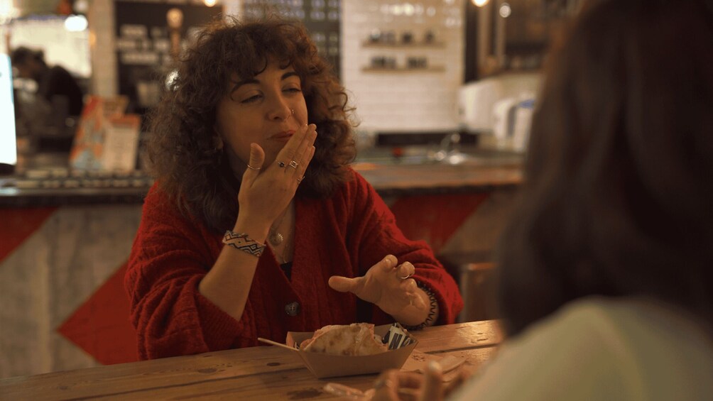 A person in a red sweater sitting at a wooden table with a bowl of food. 5