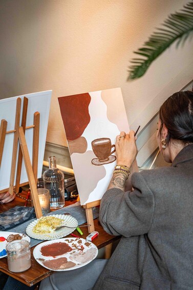 A person painting a cup on a canvas. 1