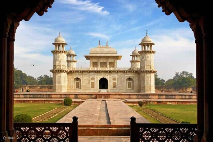 A large, historic building with two domes and two minarets, viewed from a distance through an archway. 3