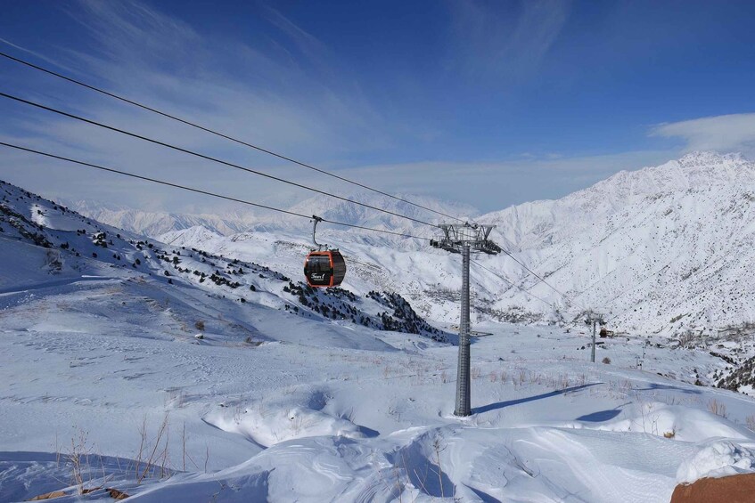 A ski lift cable car ascending a snowy mountain slope. 3