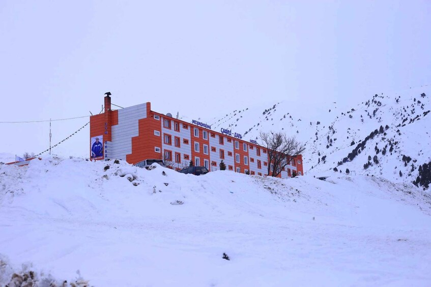 A red and white building with the sign 'MEXIMOHOKONA HOTEL' on a snowy hillside. 5