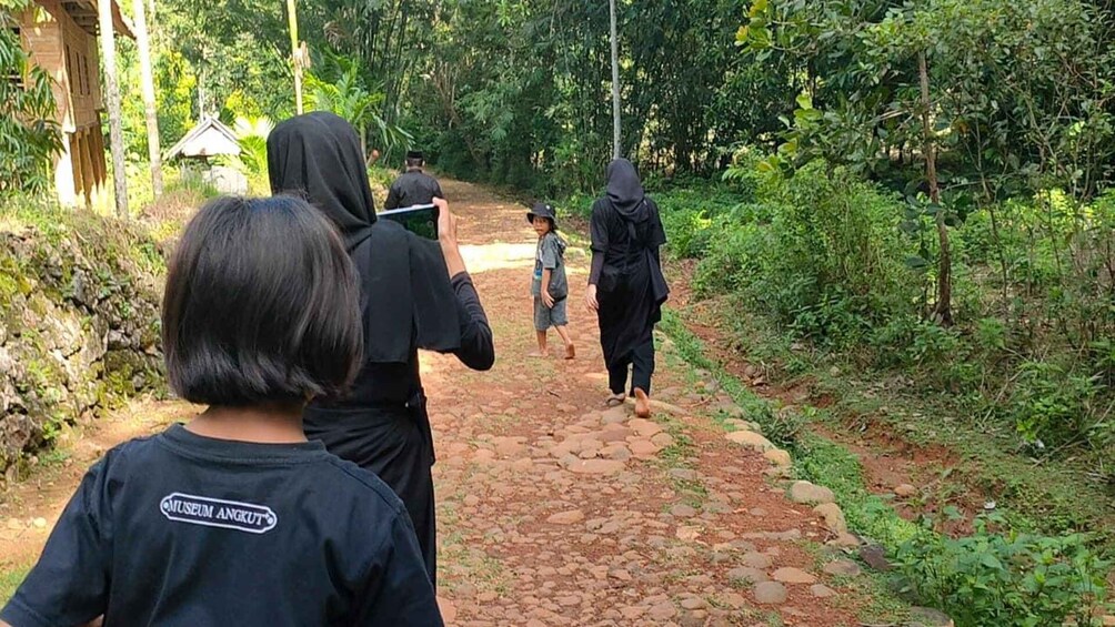 A group of people walking on a stone path surrounded by greenery. 1