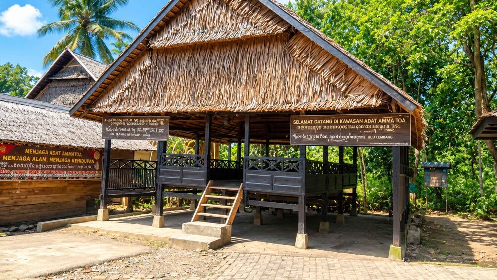 A traditional wooden structure with a thatched roof, surrounded by lush greenery and palm trees. 4