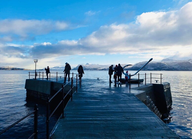 A pier extending into a calm body of water with mountains in the background. 4