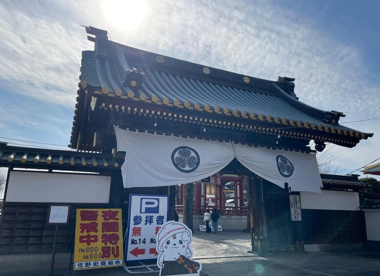 A traditional Japanese gate with a tiled roof and white curtains. 5
