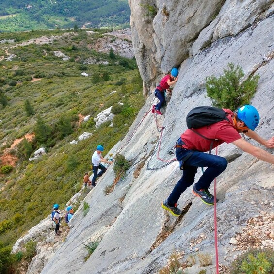A group of people rock climbing on a steep, rocky mountain slope. 1