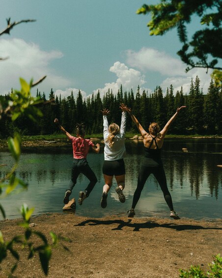 Three people jumping into a lake surrounded by trees. 2