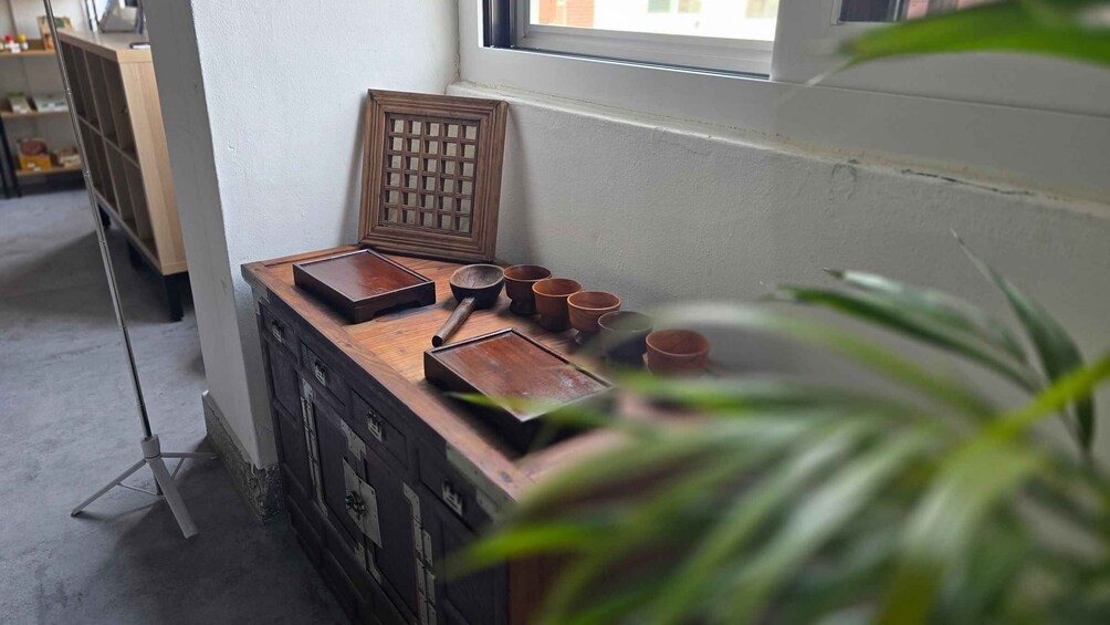 A wooden desk with various items including a tray, wooden bowls, and cups. 1