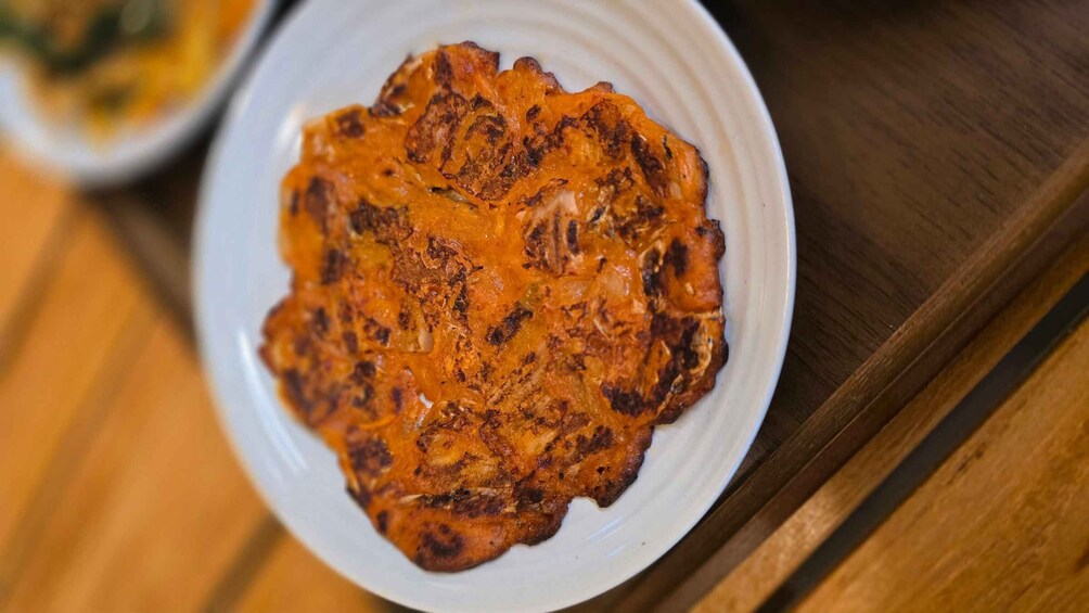 A plate of food with a golden-brown crust, possibly a type of fried or grilled dish, on a white plate. 3