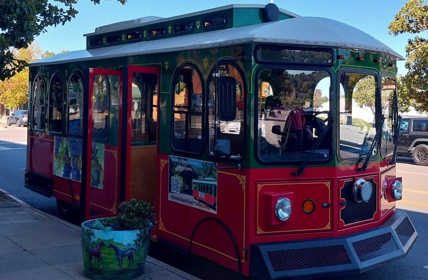 A colorful trolley with a red and green exterior, windows, and a front display. 2