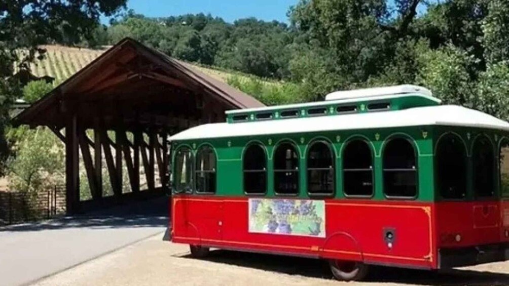 A green and red trolley parked near a wooden structure with a tiled roof. 4