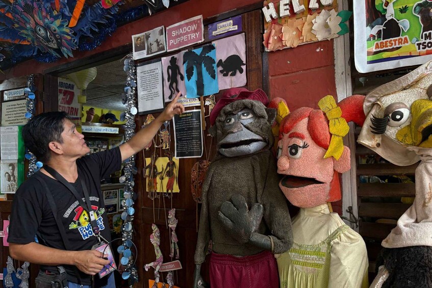 A person presenting puppets in a shop with various signs and decorations. 1