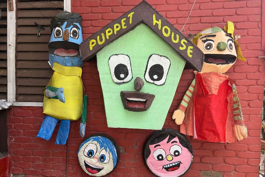 A puppet house with three puppets on a brick wall. 5