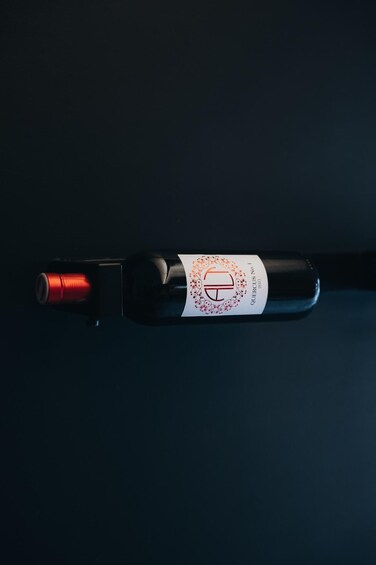 A wine bottle with a label, a cork, and a red foil. 3