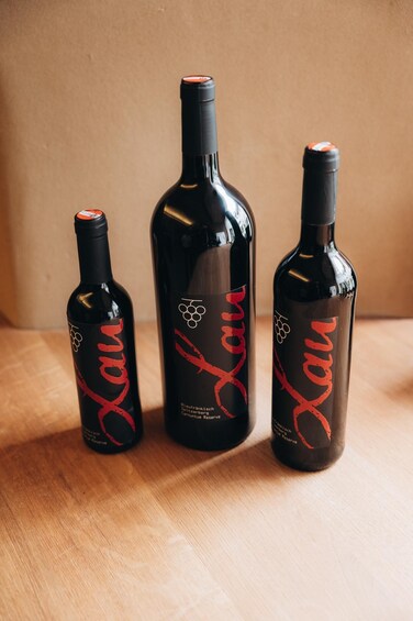 Three bottles of wine with labels on a wooden surface. 5