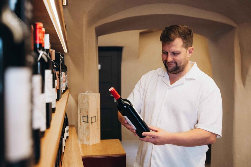 A person holding a wine bottle in a wine cellar. 1