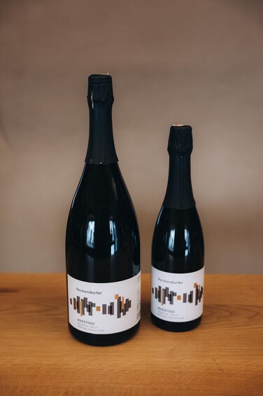 Two bottles of wine with labels on a wooden surface. 2