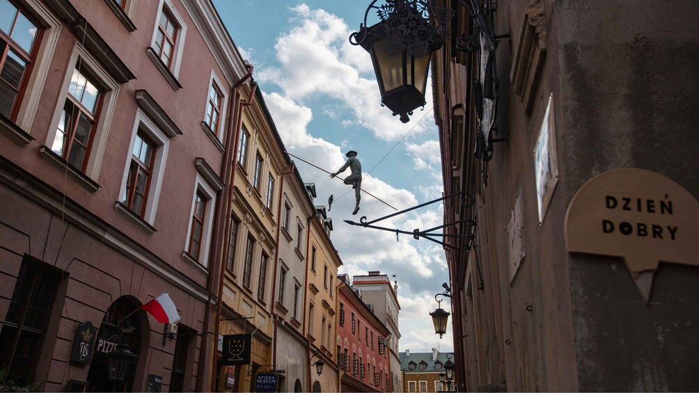 A street with buildings, a sign reading 'Dzien Dobry', and a person walking on a tightrope. 4