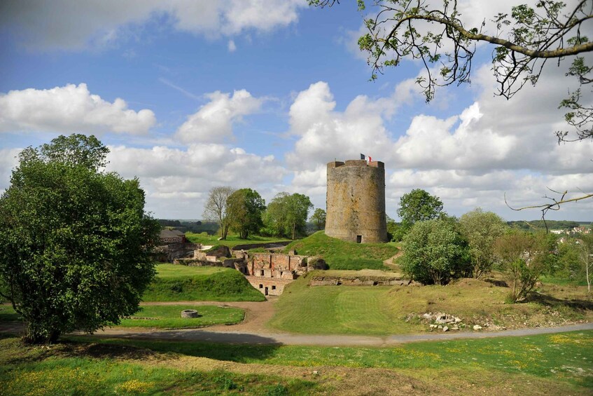 A historic stone tower surrounded by lush greenery and a clear sky. 1