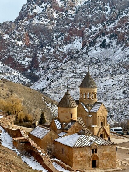 A church with multiple domes and a bell tower, surrounded by snow-covered mountains. 5