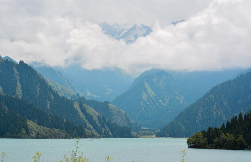 A lake surrounded by mountains with a boat in the distance. 3