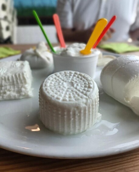 A plate with several white, round, textured food items, possibly cheese or a similar dairy product, accompanied by colorful straws. 1