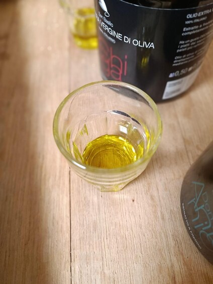 A small glass bowl containing olive oil on a wooden surface. 2