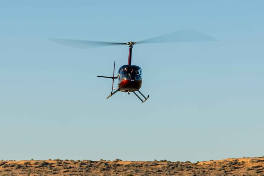 A helicopter flying over a desert landscape. 1