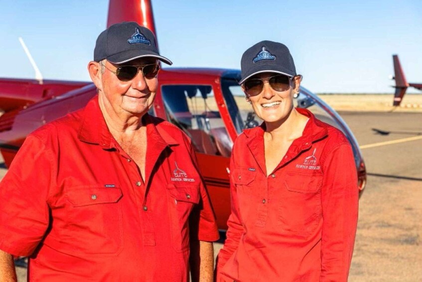 Two people in red shirts standing in front of a red aircraft. 3