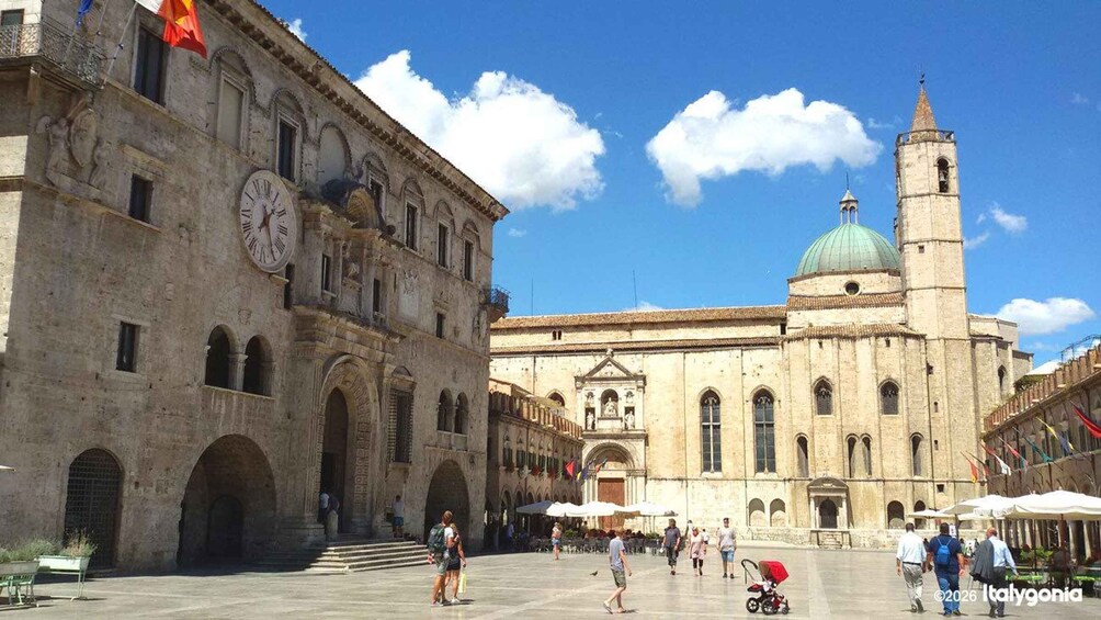 A historic square with a prominent clock tower and a large building with a dome. 1