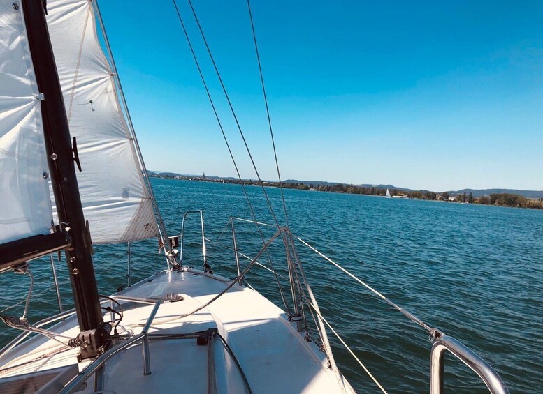 A sailboat on calm water with a clear sky and distant shoreline. 2