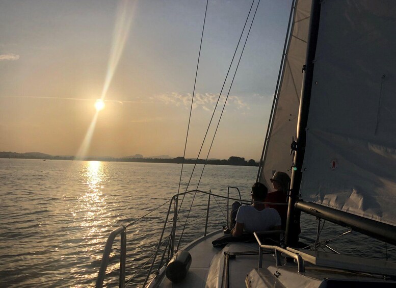 A sunset over a calm body of water with a sailboat. 3