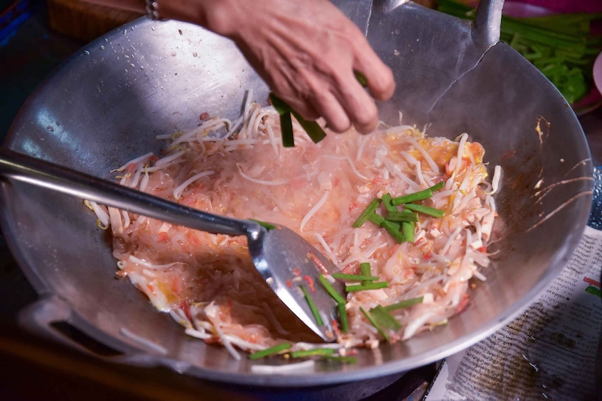 A person cooking in a wok with vegetables and meat. 4