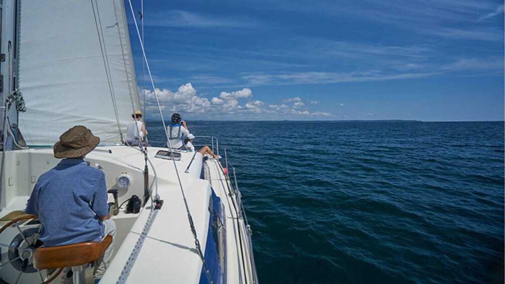 A sailboat on the ocean with people on deck. 3