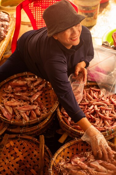 A person handling seafood, likely preparing or sorting it, with baskets and plastic containers visible. 5