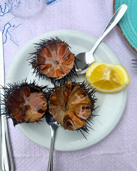 A plate with three sea urchins and a lemon half. 1