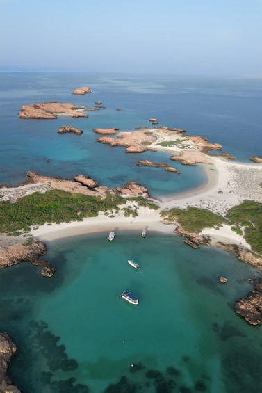 A coastal landscape with clear turquoise waters, rocky outcrops, and a sandy beach. 4