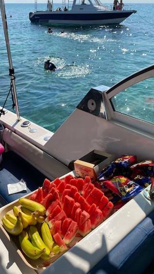 A boat with a table of watermelon and bananas, and a distant view of another boat with people. 1