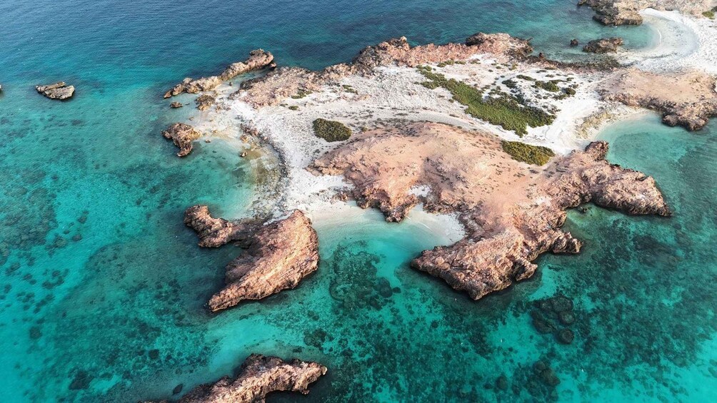 An aerial view of a rocky island with clear turquoise waters and white sandy beaches. 5