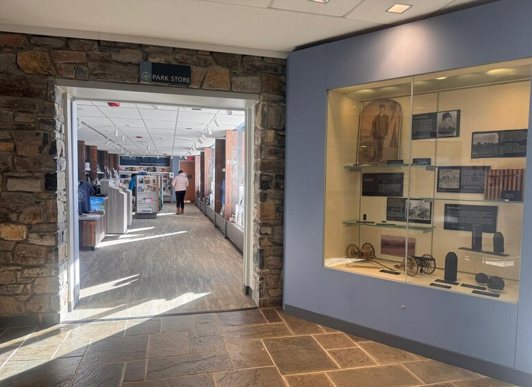 A stone wall, a park store sign, and an exhibit with historical artifacts. 5
