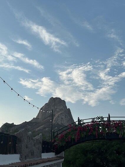 A mountain with a clear sky, string lights, and a bridge with flowers. 3