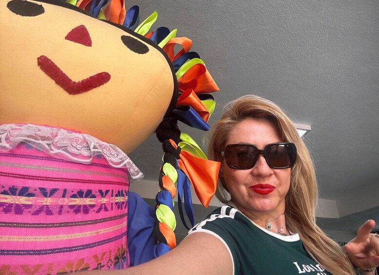 A person with a large, colorful, fabric doll with a face and a skirt. 4