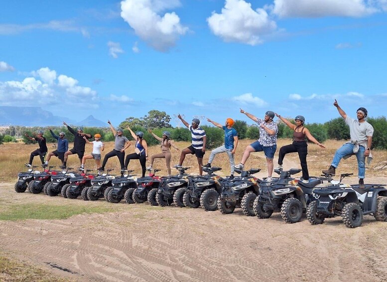 A group of people on ATVs in a field with mountains in the background. 3