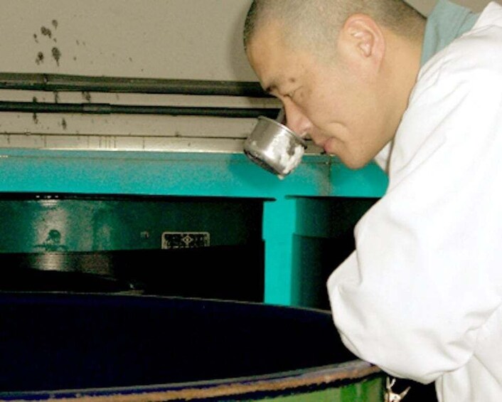 A person in a white lab coat working with a large industrial machine. 3